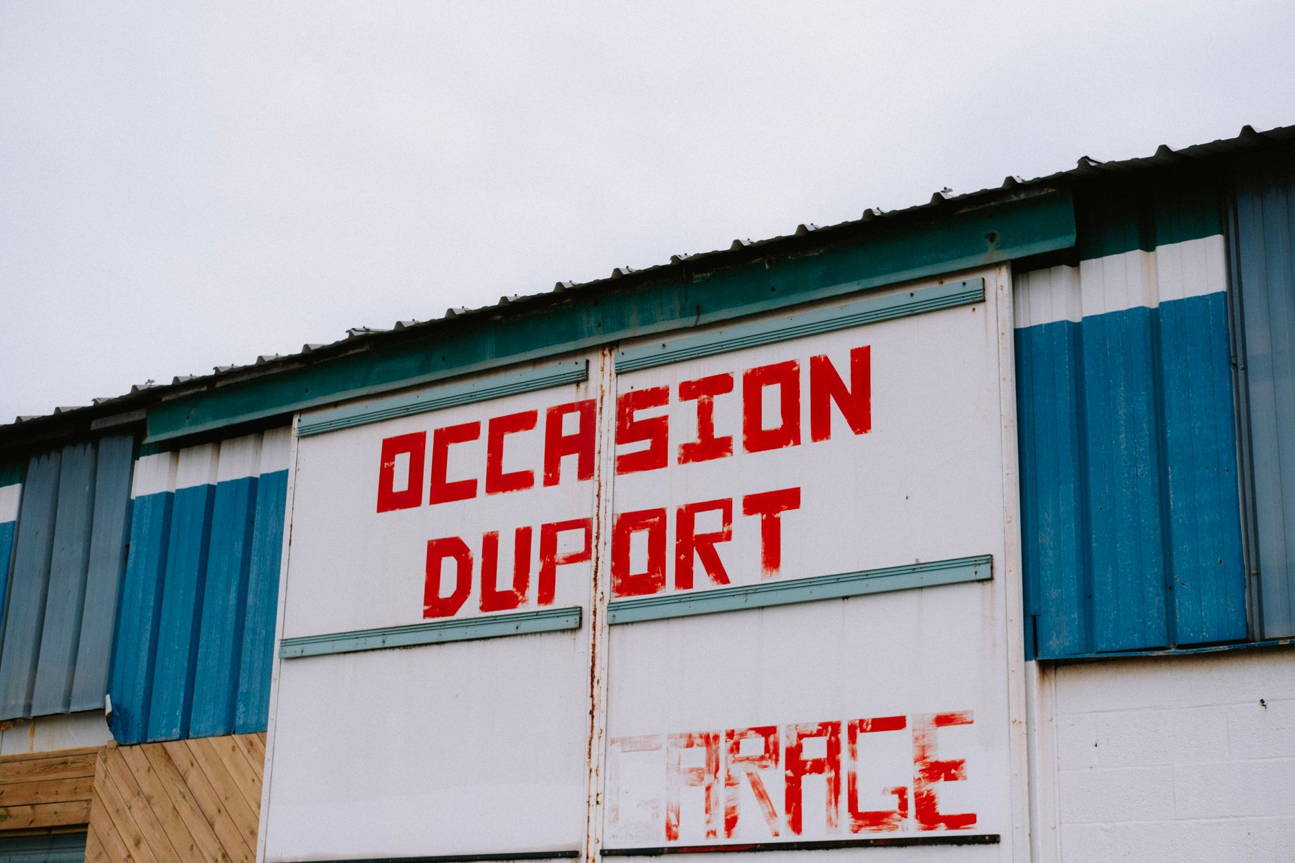 technicien posant une plaque professionnelle avec logo sur un mur extérieur d’entreprise à Dunkerque